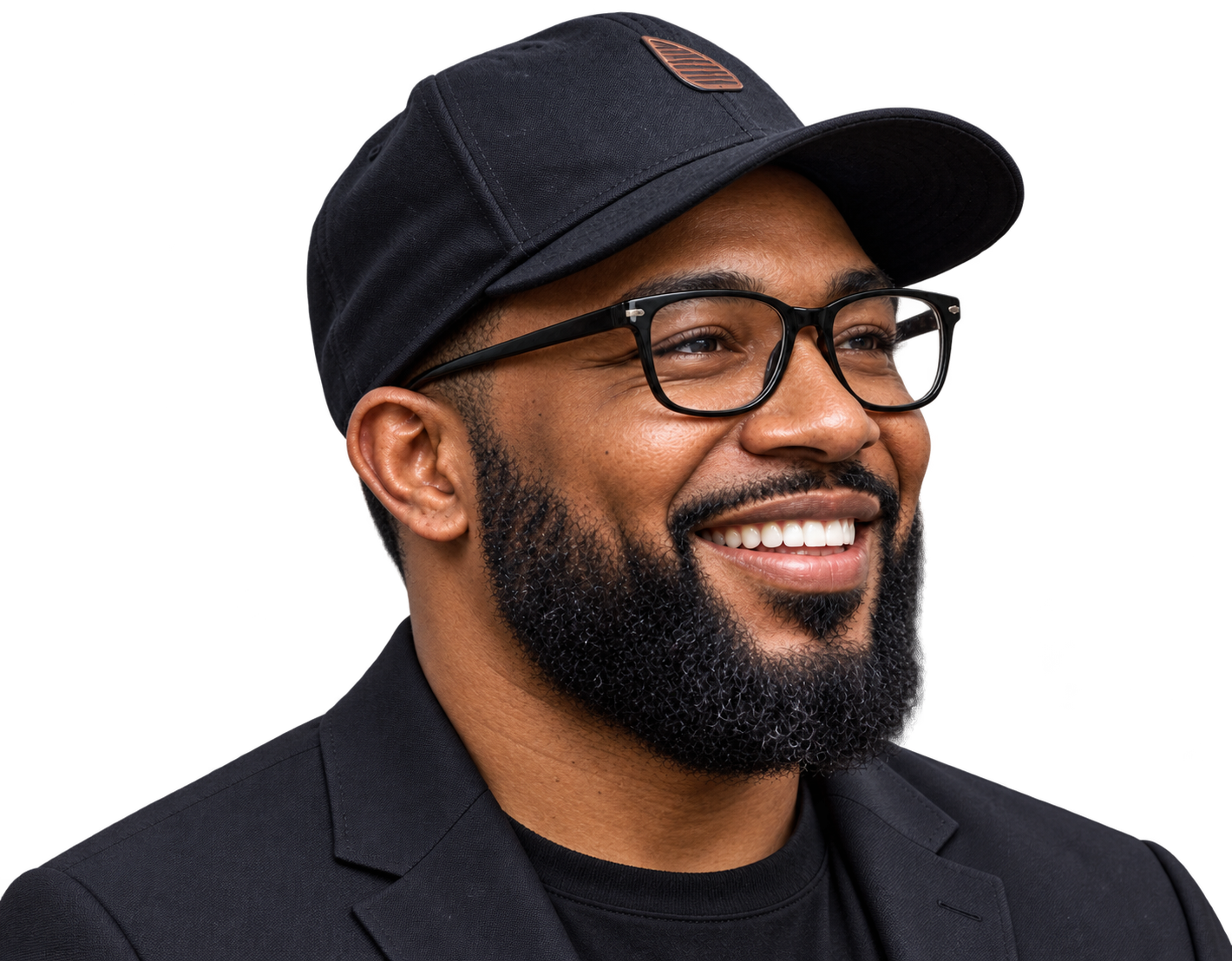 A bearded man with a black hat, black glasses, and suit. Facing to the right and smiling