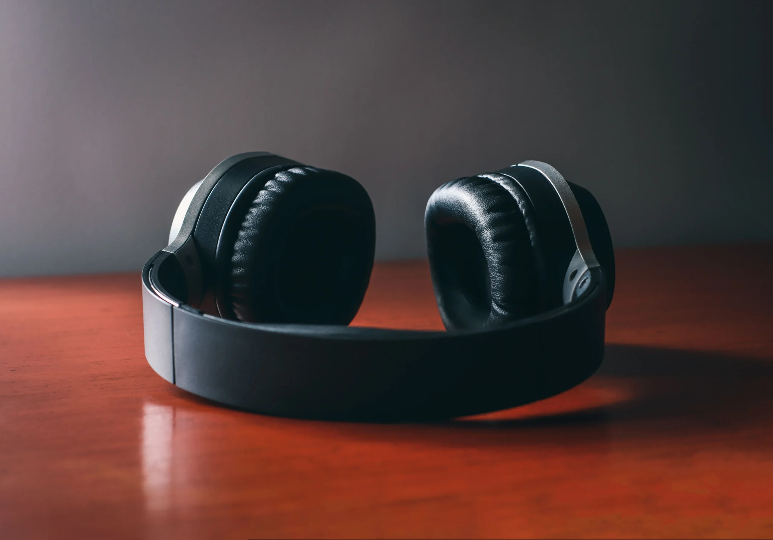 black headphones laid on a wooden desk